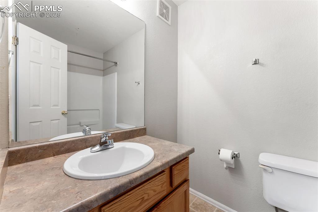 Full bath featuring vanity, light tile patterned flooring, and a textured wall