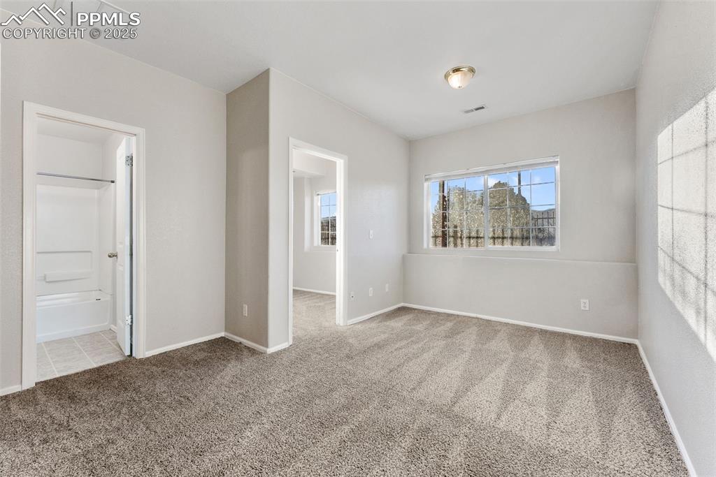 Unfurnished bedroom featuring light colored carpet and ensuite bath