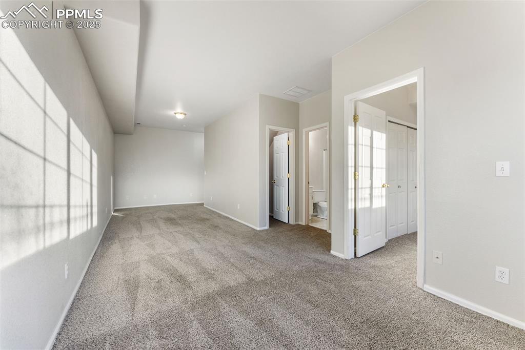 Unfurnished bedroom with light colored carpet and ensuite bath