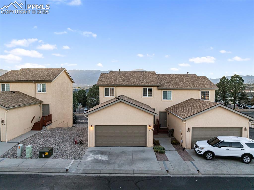 Traditional-style home with a mountain view, stucco siding, driveway, and roof with shingles