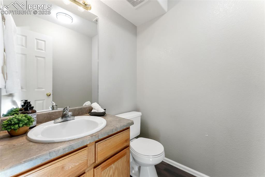 Half bathroom with vanity and dark wood-style floors