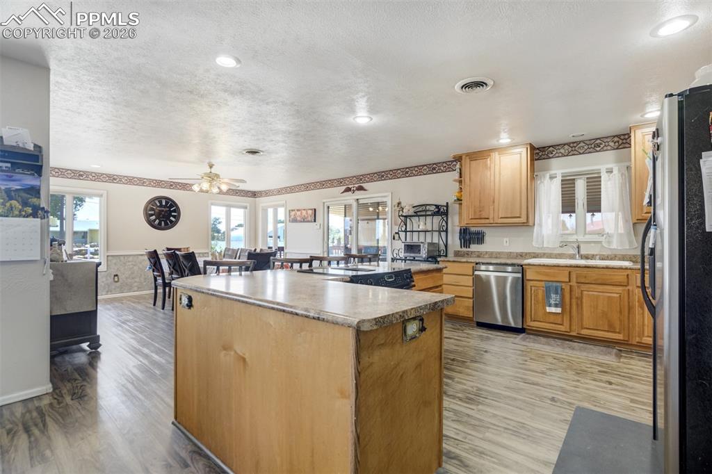 Kitchen with stainless steel appliances, a kitchen island, and a textured ceiling