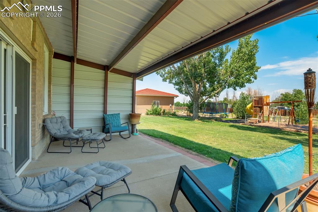 View of patio with a playground and a trampoline