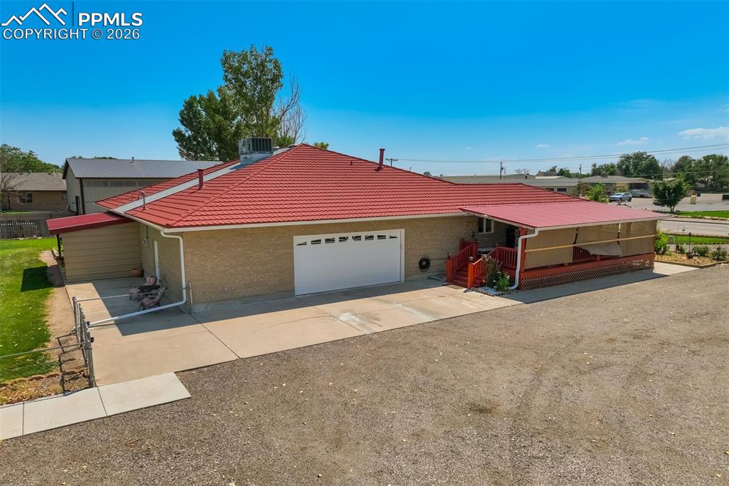 Single story home featuring an attached garage, a tile roof, brick siding, and dirt driveway