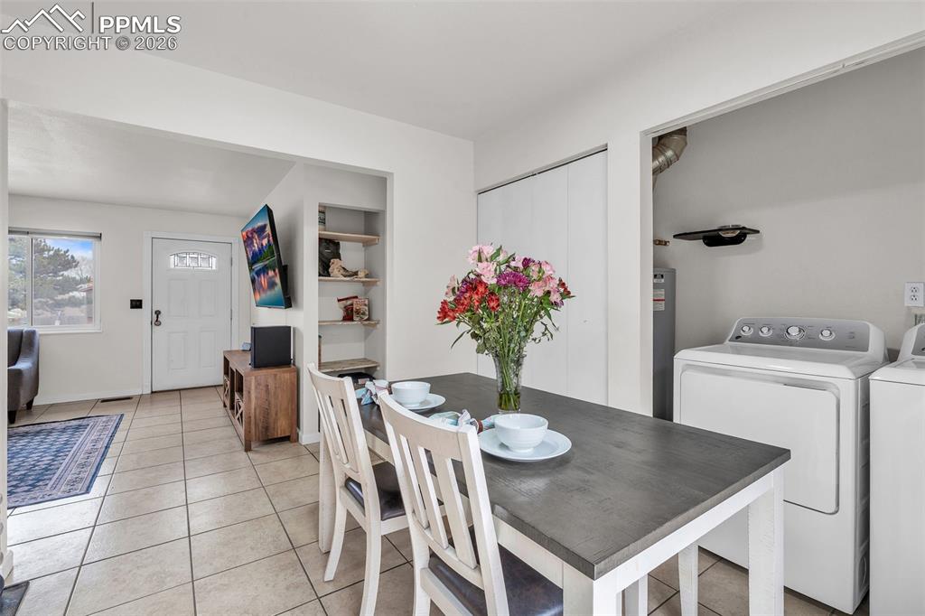 Dining area featuring light tile patterned floors, washer and clothes dryer, and water heater