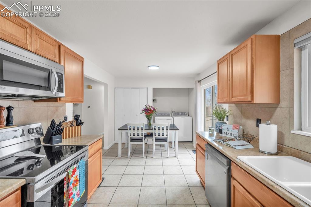 Kitchen featuring tasteful backsplash, stainless steel appliances, light countertops, and light tile patterned flooring