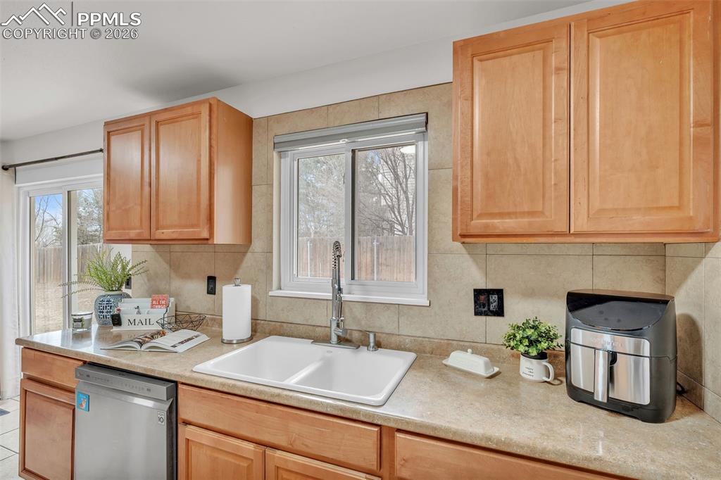 Kitchen featuring dishwasher, light countertops, and plenty of natural light