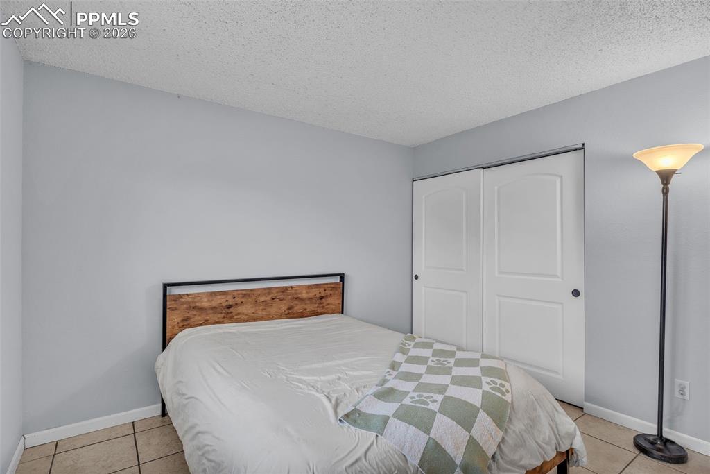 Bedroom featuring a textured ceiling, light tile patterned floors, and a closet
