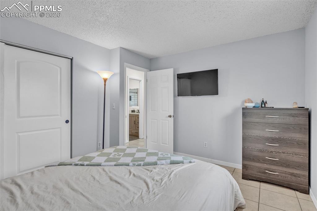 Bedroom with a textured ceiling, light tile patterned floors, and a closet