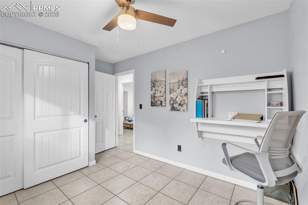Home office with light tile patterned floors and ceiling fan