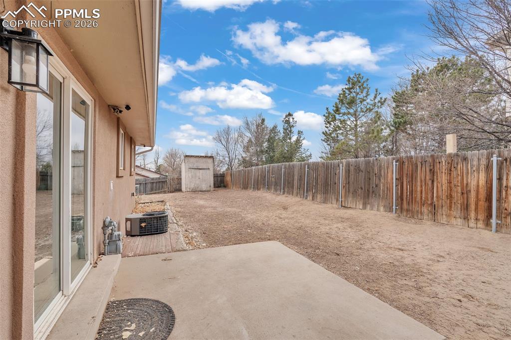 Fenced backyard featuring a patio and a shed