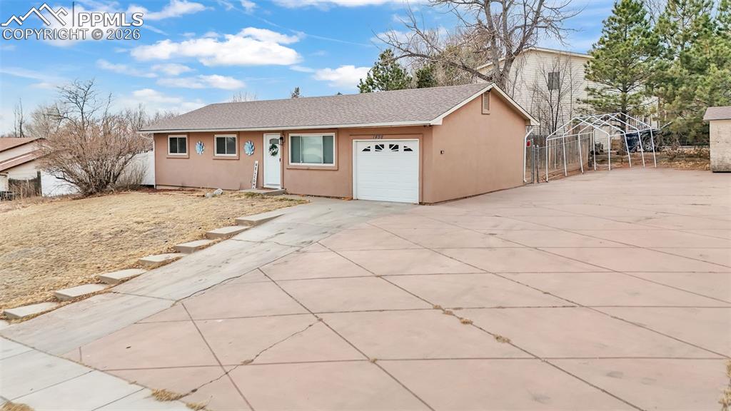 Ranch-style house with stucco siding, driveway, an attached garage, and a shingled roof