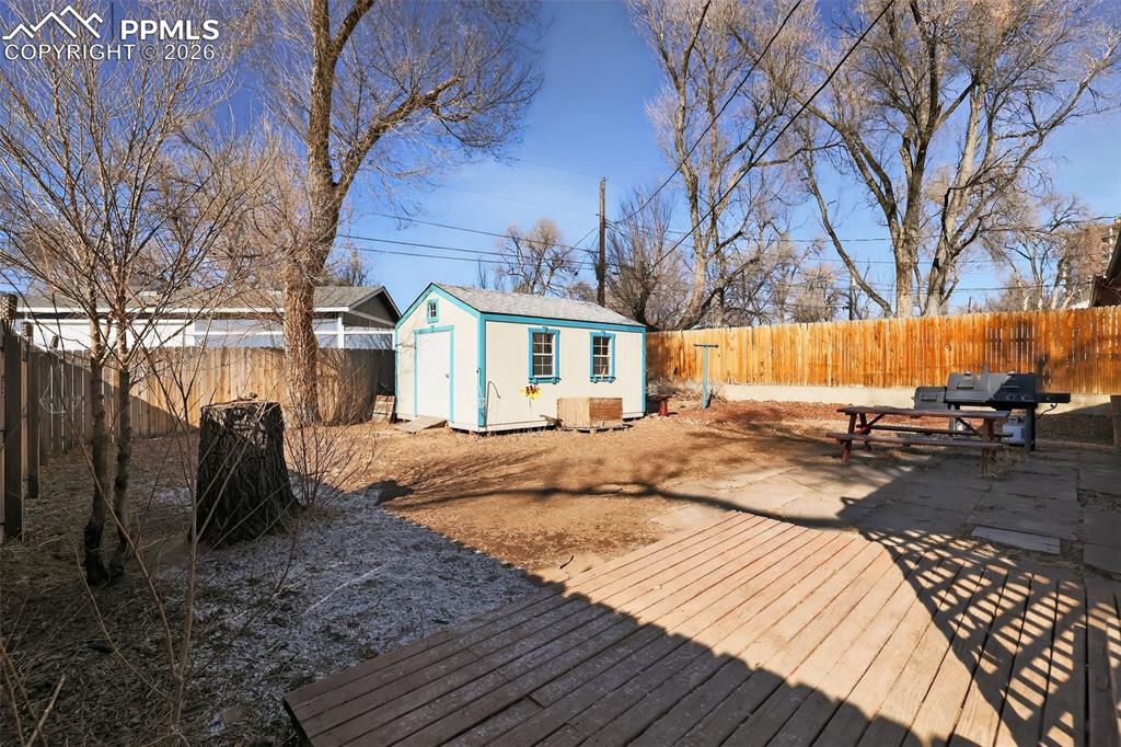 Deck featuring a fenced backyard, a storage shed, and a grill