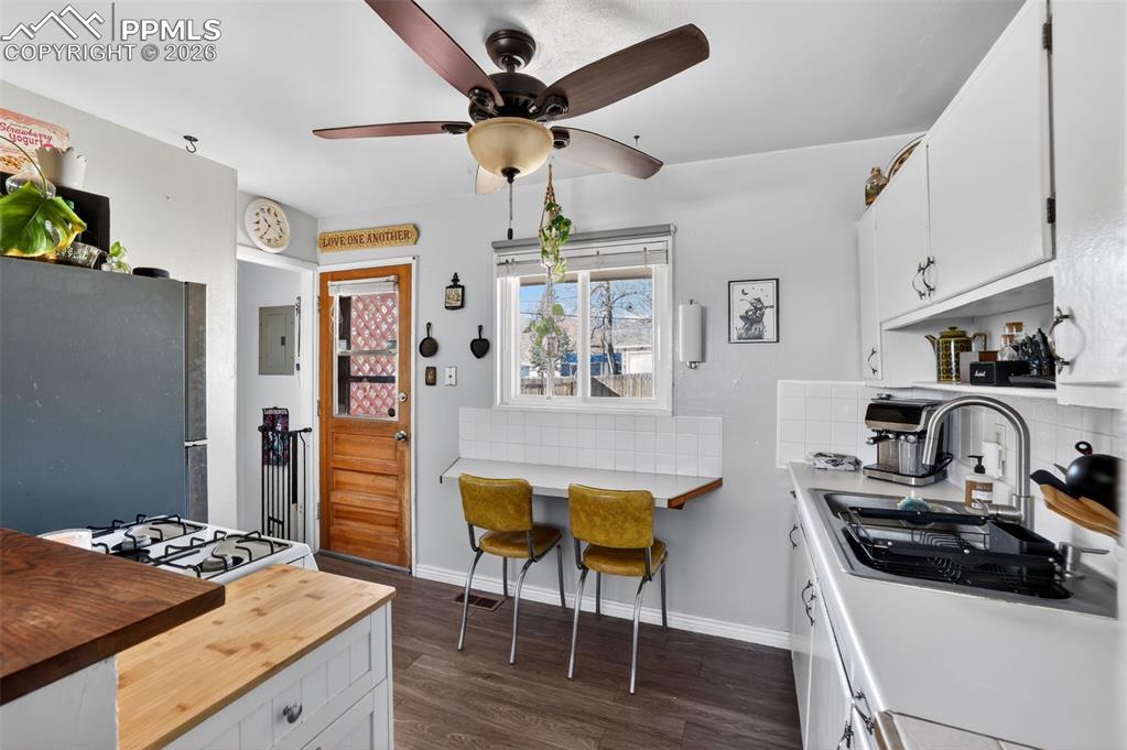 Kitchen featuring white cabinetry, butcher block countertops, freestanding refrigerator, tasteful backsplash, and dark wood finished floors