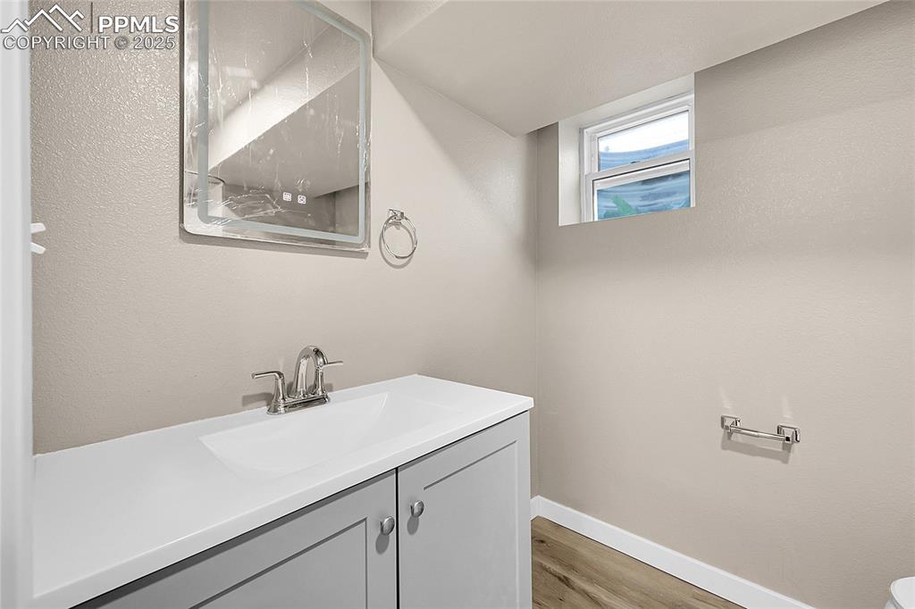 Bathroom with vanity, light wood-type flooring, and a textured wall