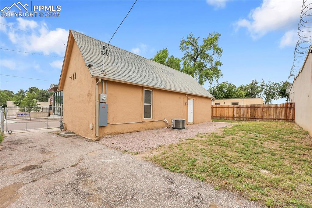 View of side of home featuring a fenced backyard, roof with shingles, and stucco siding