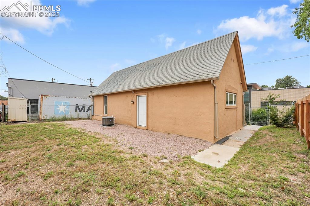 Rear view of house featuring a gate, stucco siding, and roof with shingles