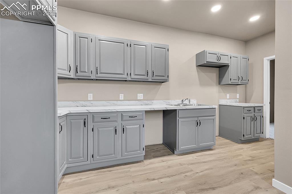 Kitchen featuring gray cabinets, light countertops, light wood-type flooring, and recessed lighting
