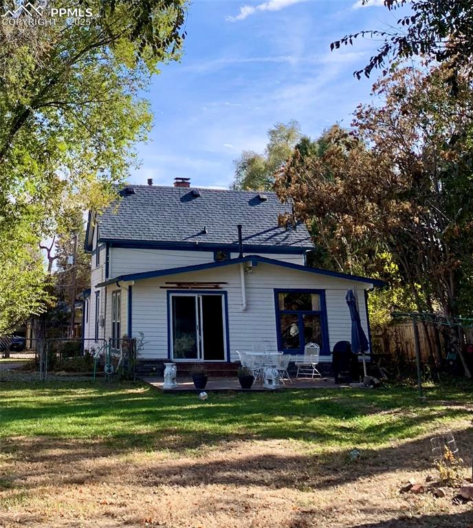 Rear view of house with a chimney, roof with shingles, and a patio area