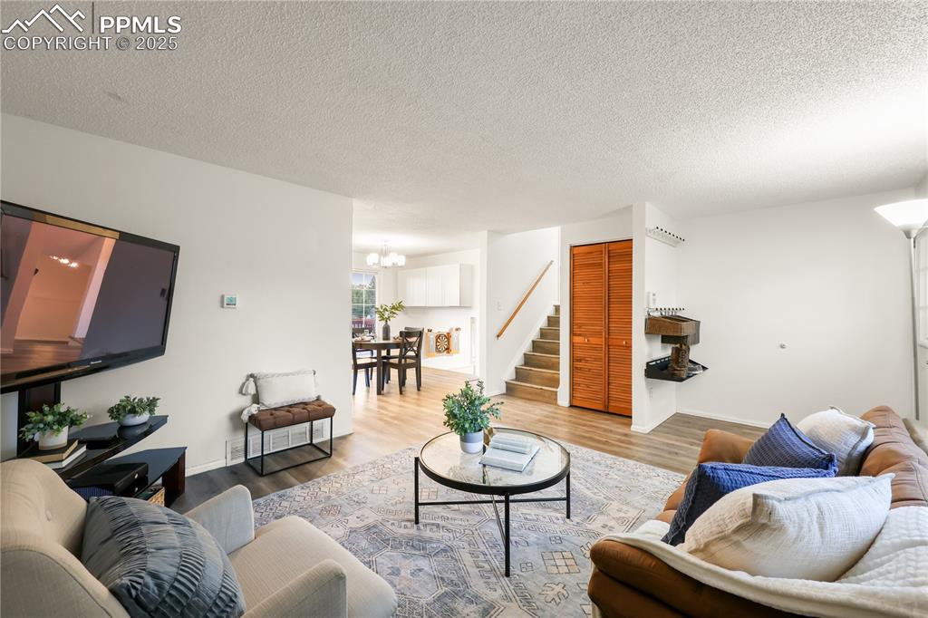 Living room with wood finished floors, a textured ceiling, stairway, and a chandelier