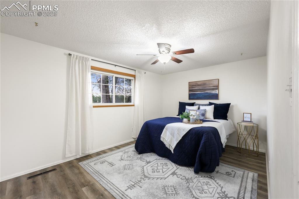 Bedroom with a textured ceiling, wood finished floors, and ceiling fan