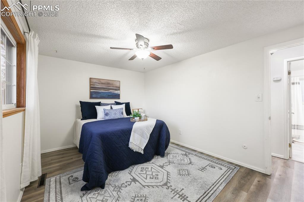 Bedroom with wood finished floors, ceiling fan, and a textured ceiling