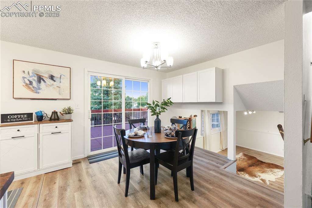 Dining space featuring a textured ceiling, light wood finished floors, and a chandelier