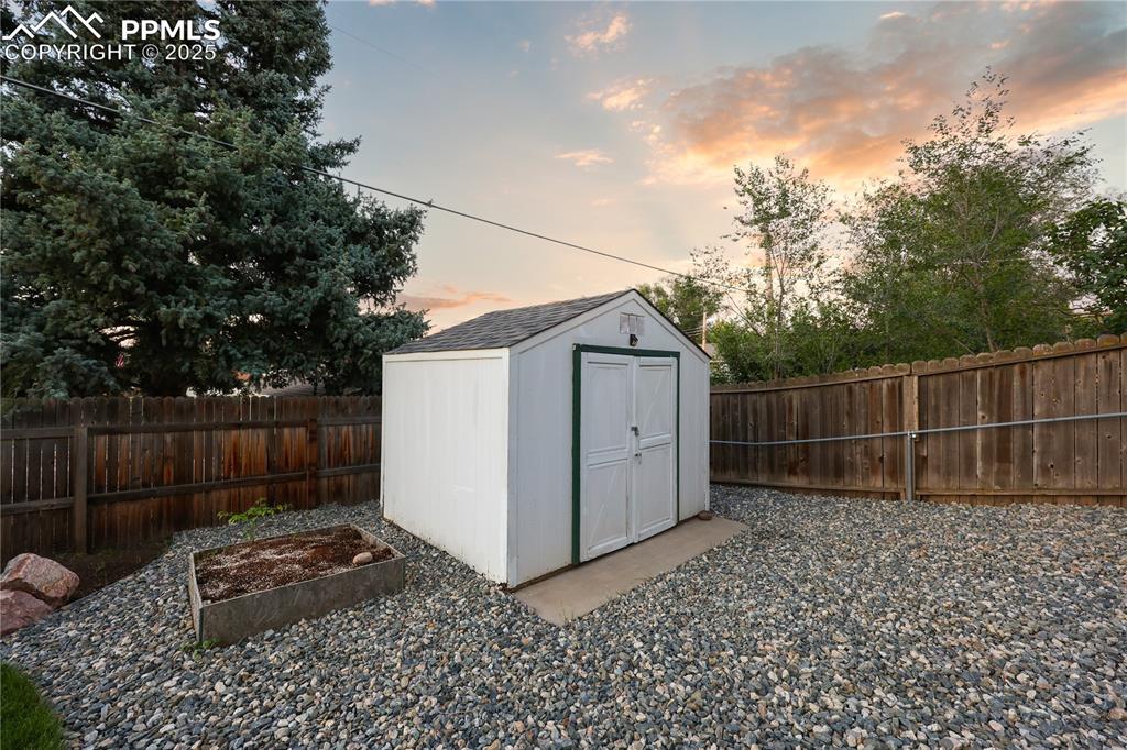 View of shed with a fenced backyard and a vegetable garden