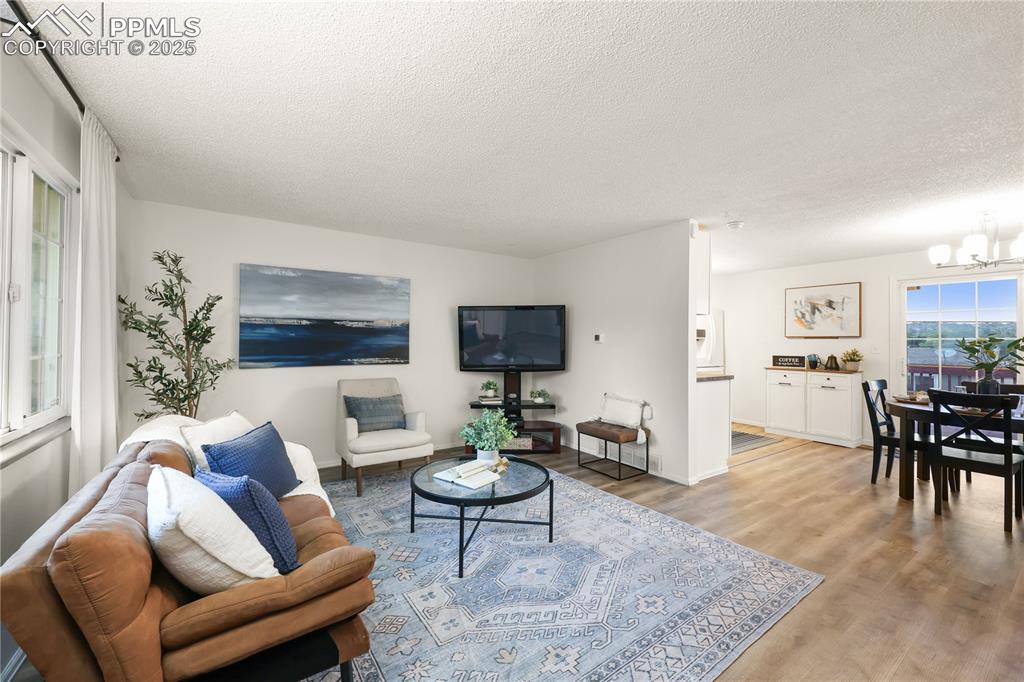 Living area with light wood-type flooring, a textured ceiling, and a chandelier