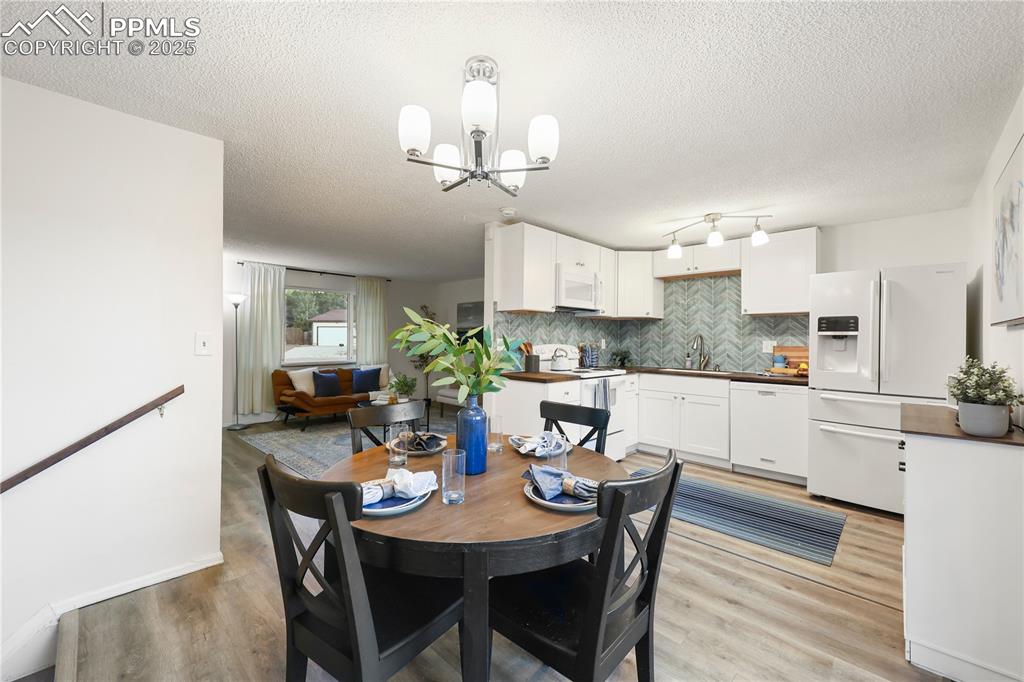 Dining room featuring light wood-style floors, a textured ceiling, and a chandelier