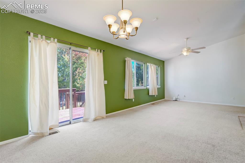 Carpeted spare room with a chandelier and ceiling fan