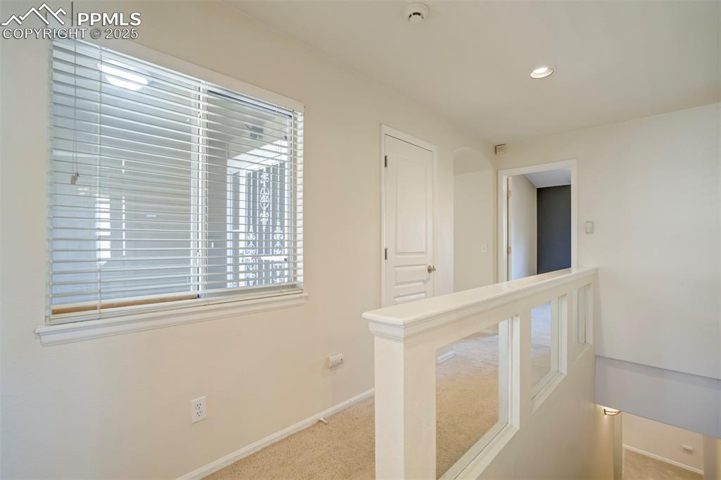 Hall featuring an upstairs landing, light colored carpet, recessed lighting, and plenty of natural light
