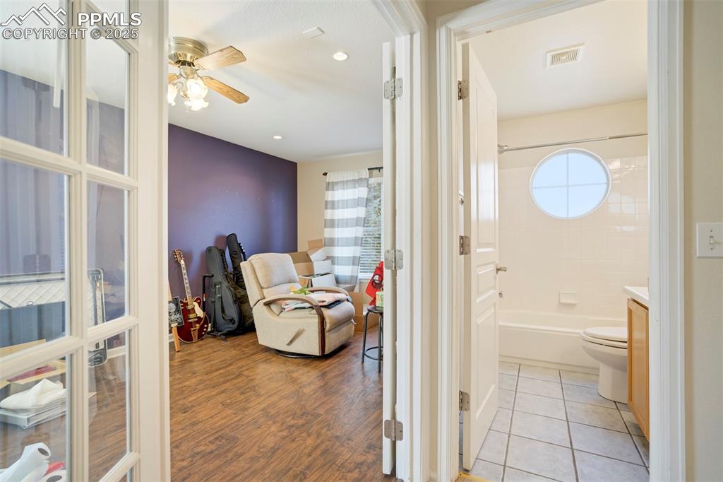 Bathroom featuring vanity,  shower combination, light wood-type flooring, a ceiling fan, and recessed lighting