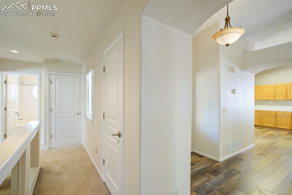 Corridor with light wood-style flooring and arched walkways