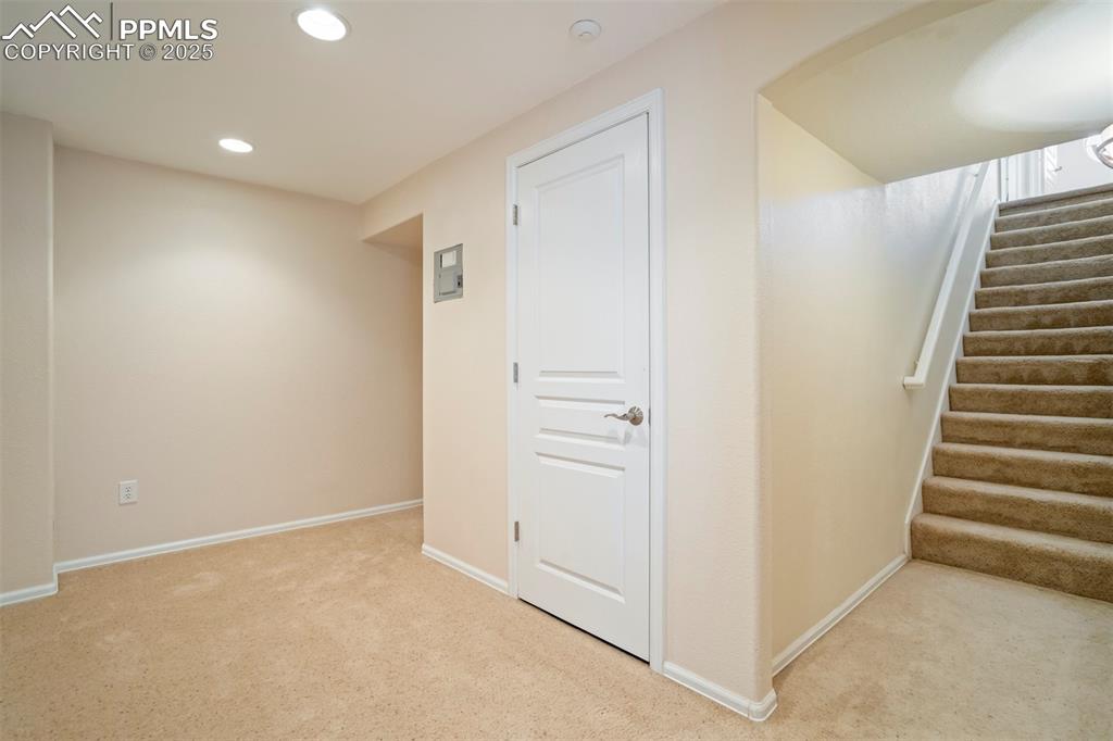 Below grade area featuring light carpet, recessed lighting, and stairway