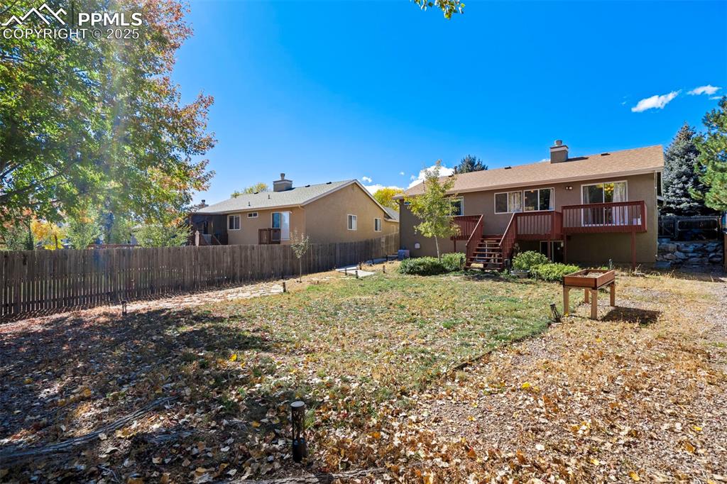 Back of property featuring a chimney, a fenced backyard, a wooden deck, and stairs