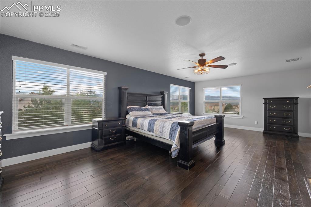 Large Bedroom with a textured ceiling, dark wood-style floors, and ceiling fan