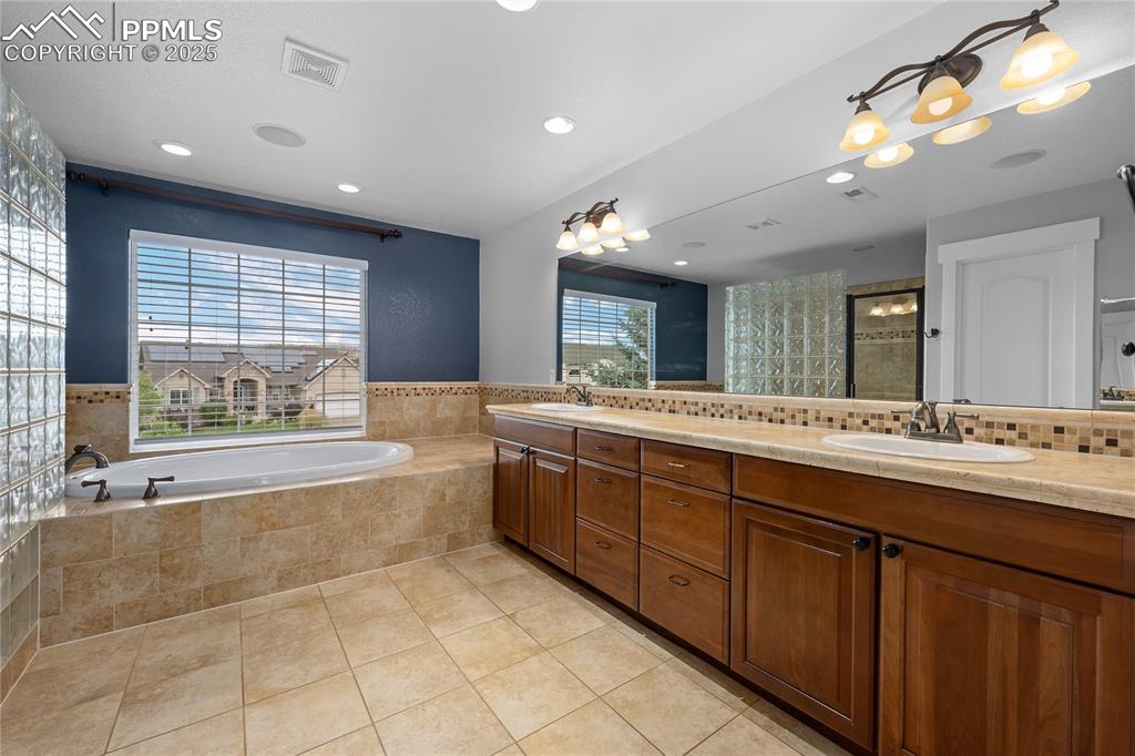 Full bathroom featuring a garden tub, light tile patterned floors, double vanity, recessed lighting, and a shower stall