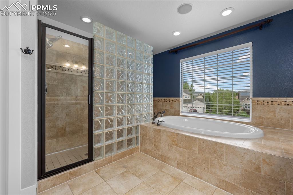 Bathroom featuring a stall shower, a garden tub, tile patterned flooring, and recessed lighting