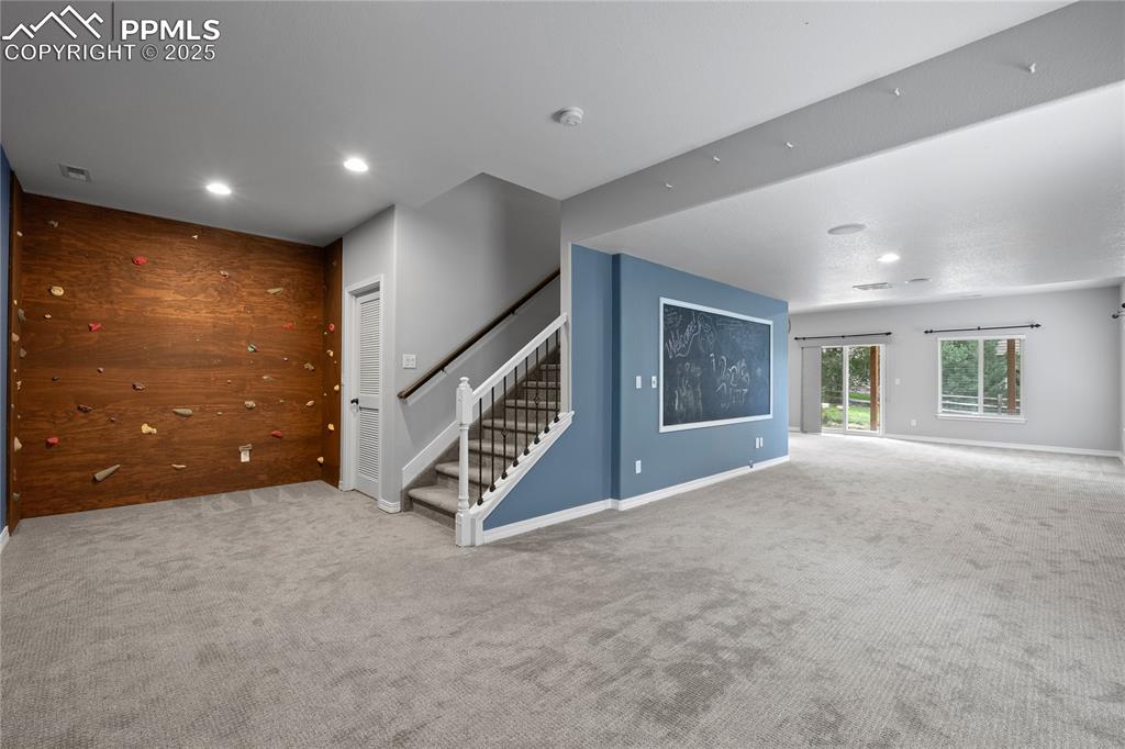 Basement family room with carpet floors, stairs and recessed lighting