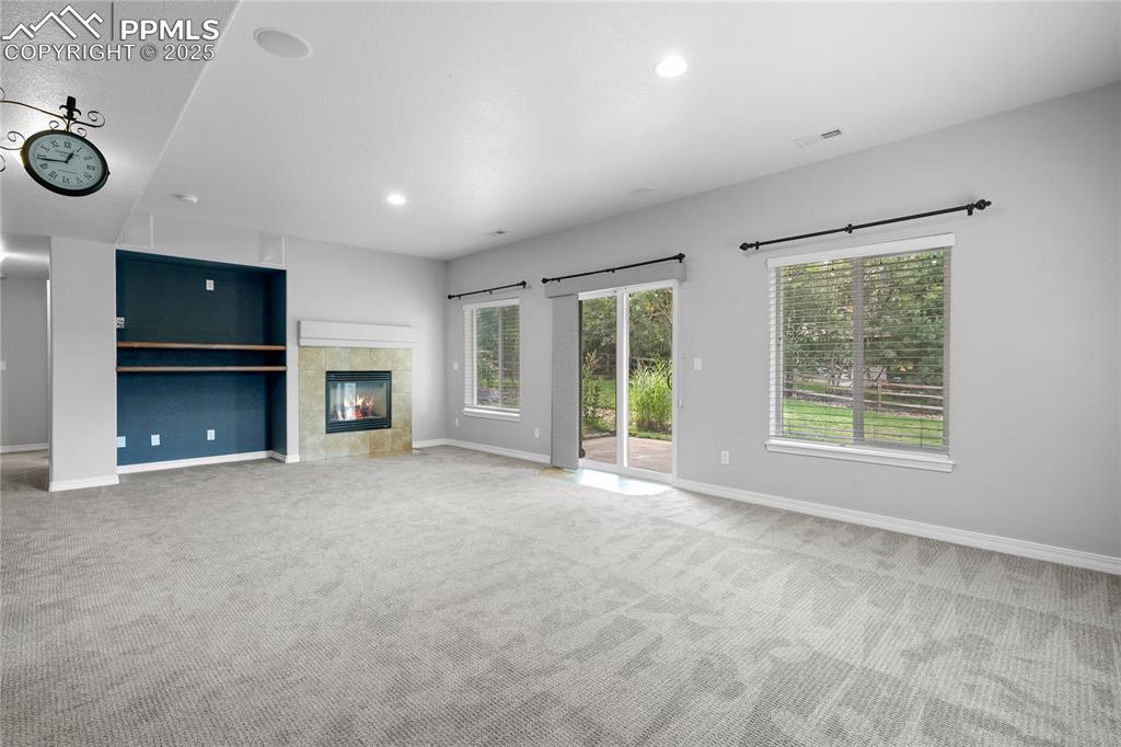 Basement family room featuring a tile fireplace, carpet, plenty of natural light, and recessed lighting