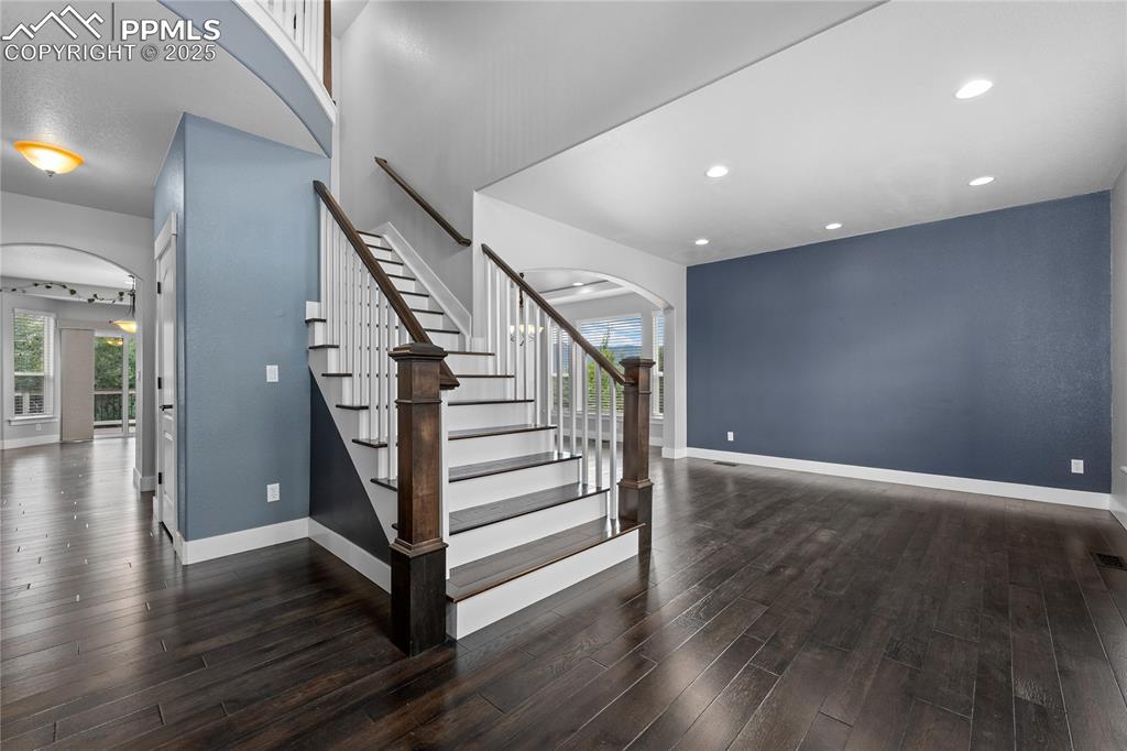 Stairs featuring arched walkways, wood finished floors, and recessed lighting