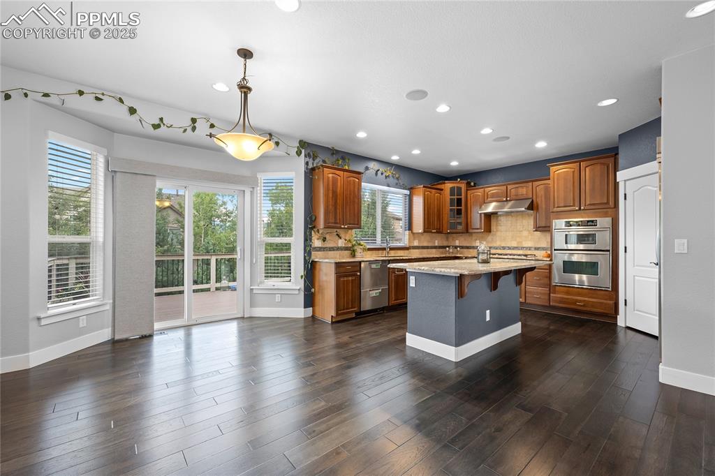 Kitchen with a breakfast bar, tasteful backsplash, glass insert cabinets, light stone countertops, and a kitchen island