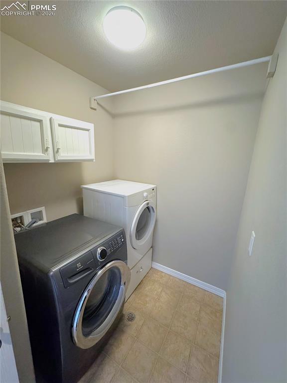 Upper-Level Laundry Room with Cabinets & Hanging Rod
