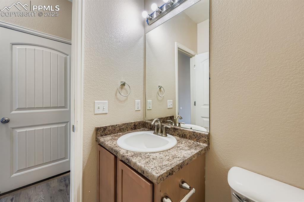 Bathroom featuring a textured wall, vanity, and wood finished floors