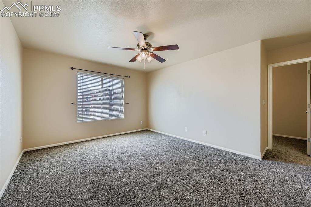 Empty room with carpet flooring, a ceiling fan, and a textured ceiling