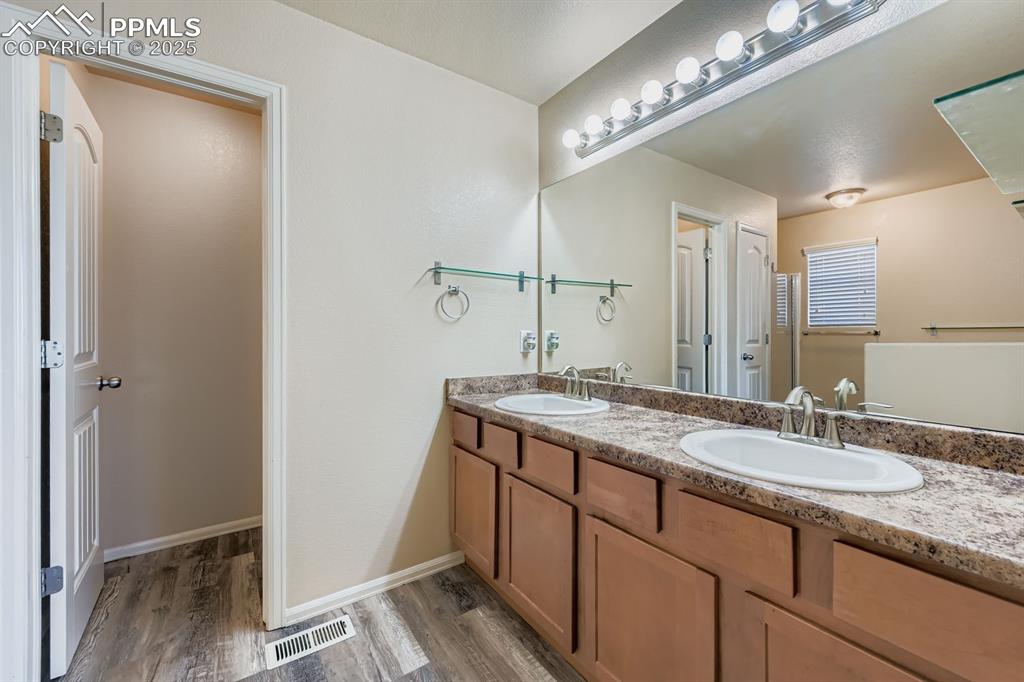 Full bath with light wood-style floors and double vanity