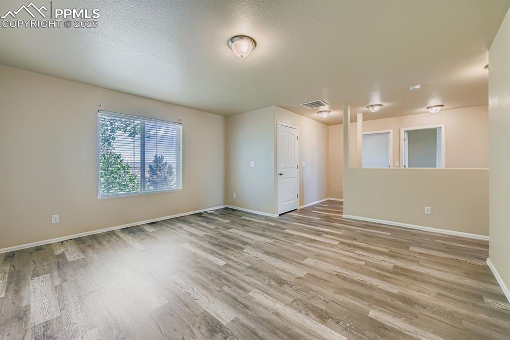 Empty room with light wood-type flooring and a textured ceiling
