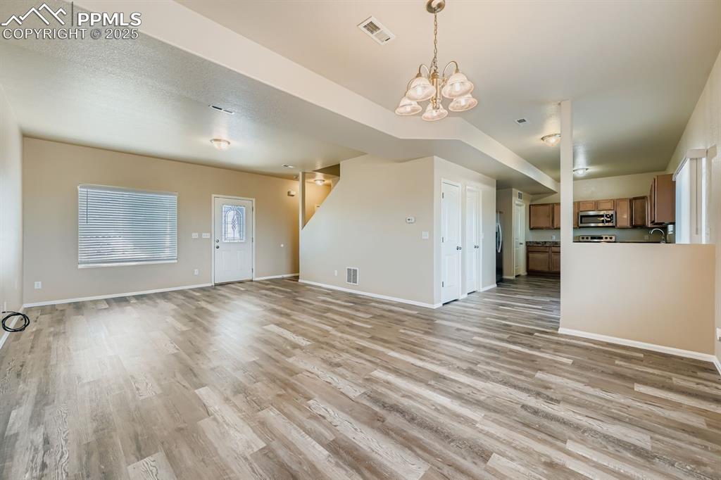 Unfurnished living room featuring light wood-style flooring and a chandelier