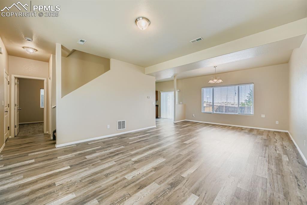 Unfurnished living room featuring light wood-type flooring and a chandelier